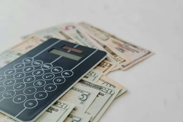 A close-up of a calculator and US dollar banknotes, symbolizing financial calculation and budgeting.